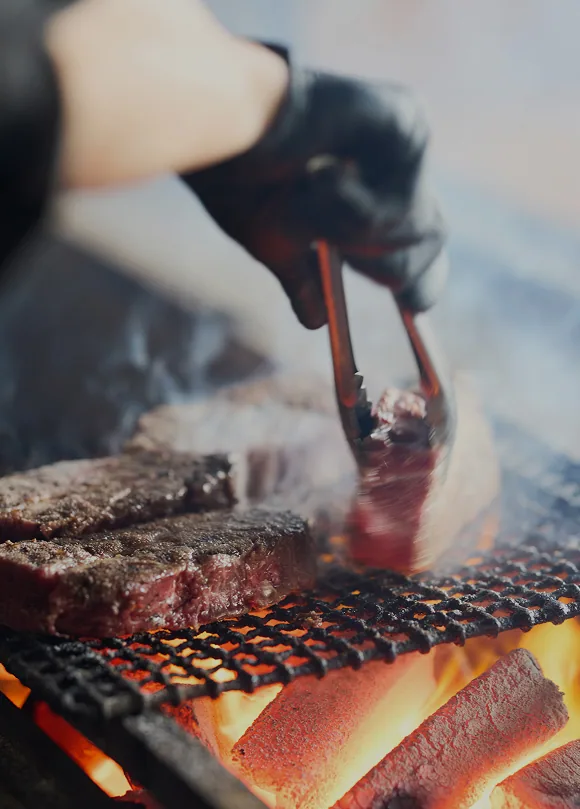 炭火の上で肉を焼き上げるシェフの手元